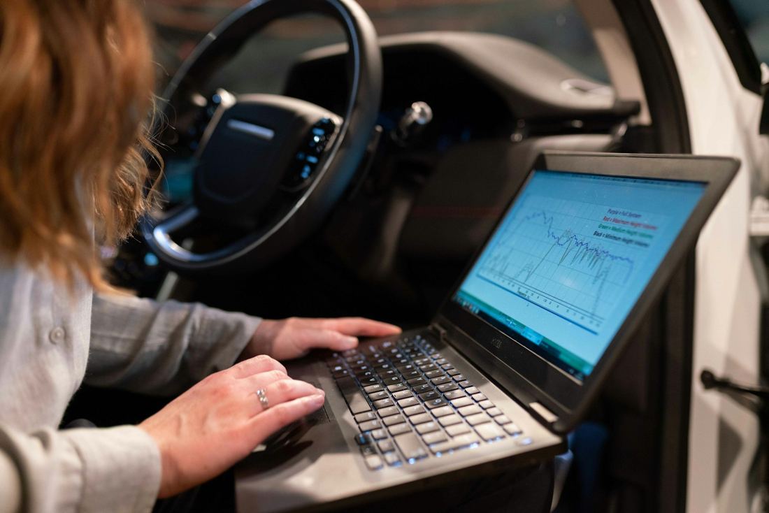Technician running a diagnostic scan on a laptop inside a car