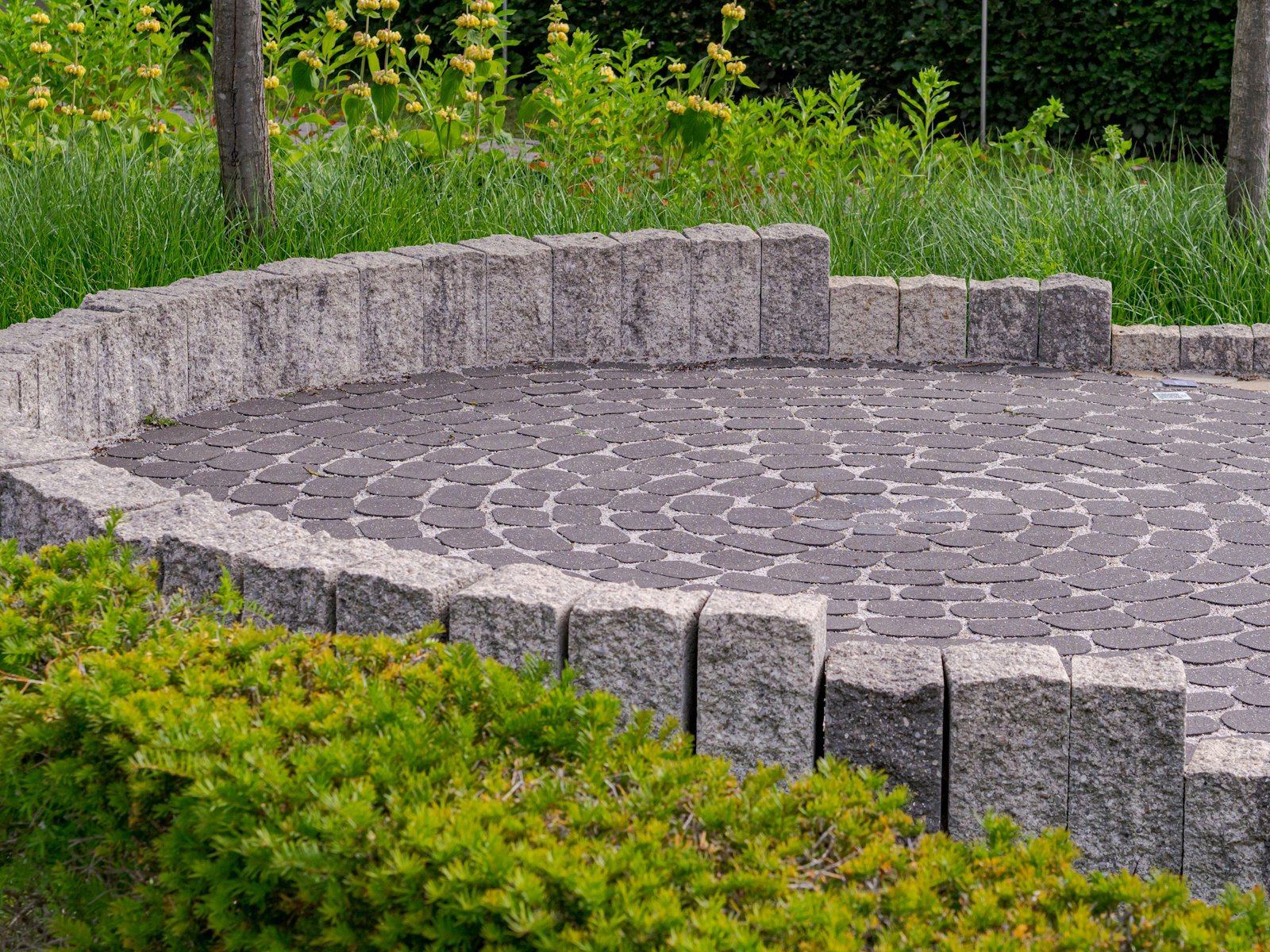 Round paver patio edged with stone and plantings